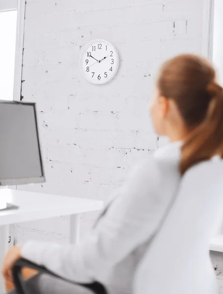 Mujer de negocios mirando el reloj de pared en la oficina — Foto de Stock