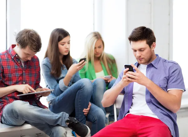 Estudiantes mirando dispositivos en la escuela — Foto de Stock