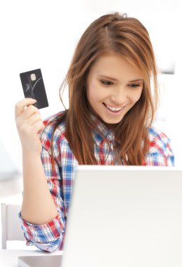 Happy teenage girl with laptop and credit card clipart