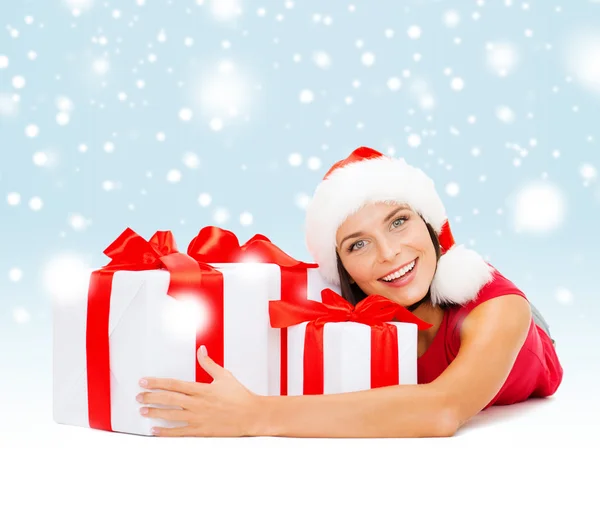 Mujer sonriente en sombrero de ayudante de santa con cajas de regalo —  Fotos de Stock