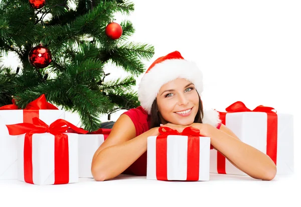 Mujer sonriente en sombrero de ayudante de santa con cajas de regalo — Foto de Stock