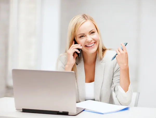 Businesswoman with smartphone in office Stock Picture