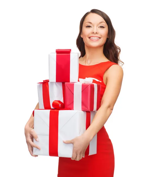 Mujer sonriente en vestido rojo con muchas cajas de regalo —  Fotos de Stock