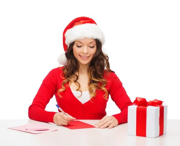 Mujer sonriente en sombrero de ayudante de santa con postal — Foto de Stock