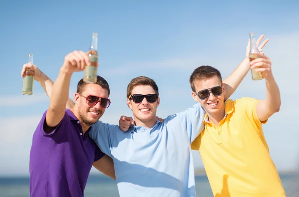 Vänner på stranden med flaskor av dryck — Stockfoto