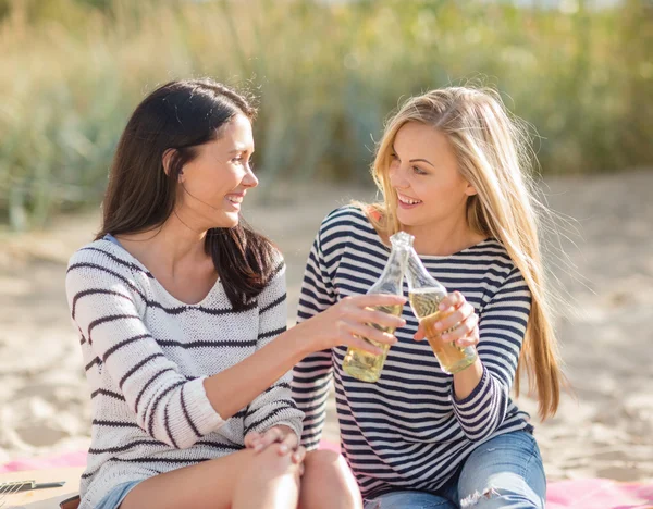 Meisjes met dranken op het strand — Stockfoto