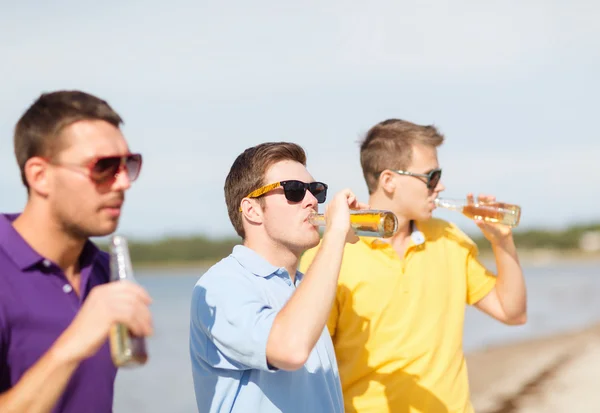 Amigos na praia com garrafas de bebida — Fotografia de Stock
