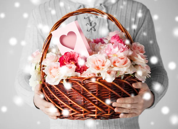 Man holding basket full of flowers and postcard — Stock Photo, Image