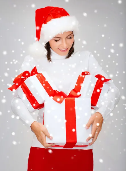 Vrouw in helper kerstmuts met vele geschenkdozen — Stockfoto