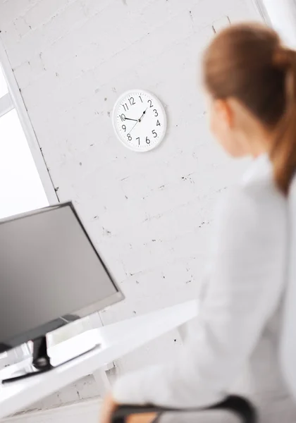 Zakenvrouw kijken naar de klok van de muur in office — Stockfoto