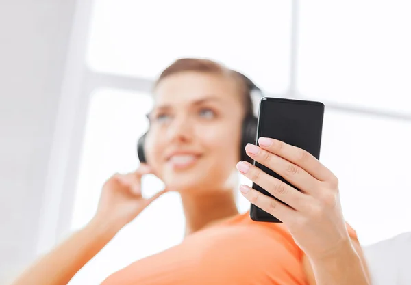 Mujer con auriculares y smartphone en casa — Foto de Stock