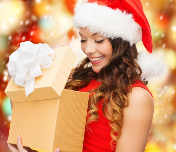 Femme souriante en santa chapeau d'aide avec boîte cadeau — Photo