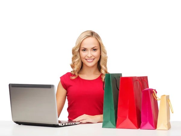 Mulher com sacos de compras e computador portátil — Fotografia de Stock