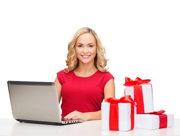 Woman with gift boxes and laptop computer — Stock Photo, Image