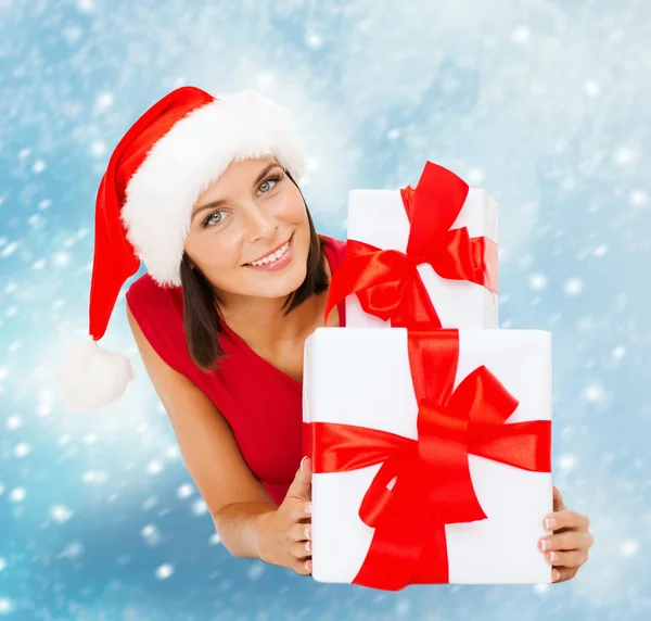 Mujer sonriente en sombrero de ayudante de santa con cajas de regalo — Foto de Stock