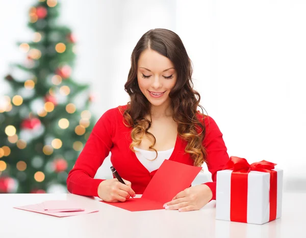 Mujer sonriente en ropa roja con postal — Foto de Stock