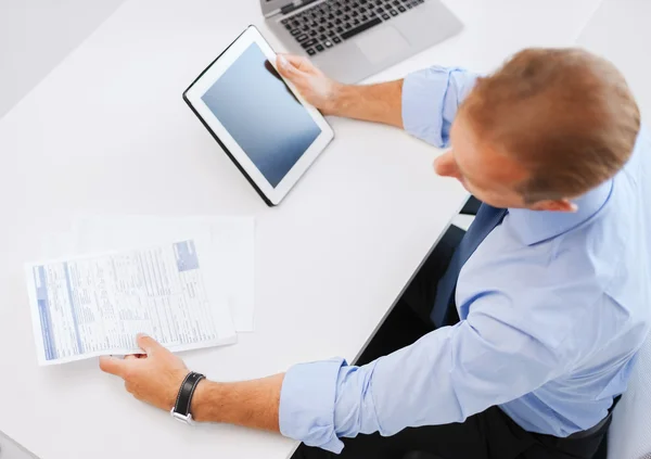 Affärsman med TabletPC och papper i office — Stockfoto