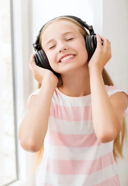 Menina com fones de ouvido em casa — Fotografia de Stock