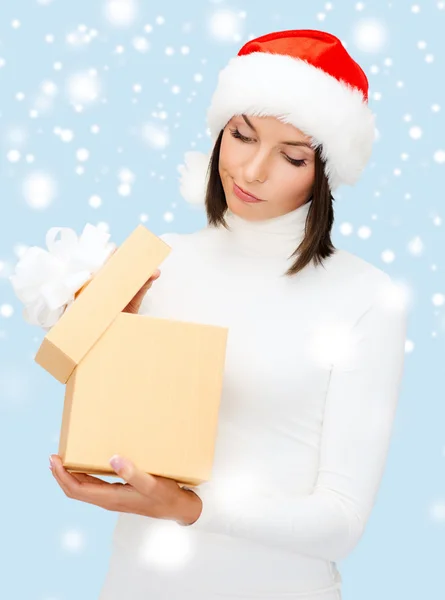 Mulher suspeita em Papai Noel chapéu auxiliar com caixa de presente — Fotografia de Stock