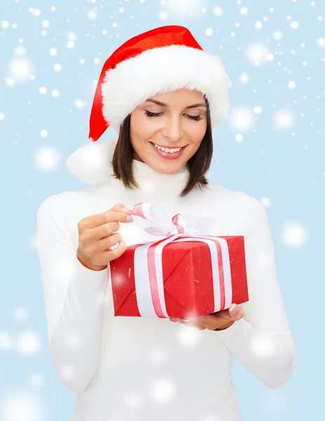 Mujer sonriente en sombrero de ayudante de santa con caja de regalo — Foto de Stock