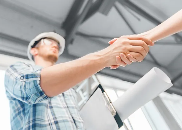 Builder z blueprint drżenie ręki partnera — Zdjęcie stockowe