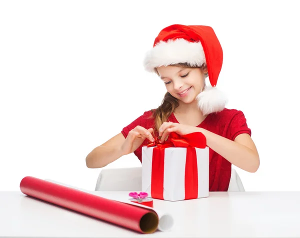 Chica sonriente en sombrero de ayudante de santa con caja de regalo —  Fotos de Stock