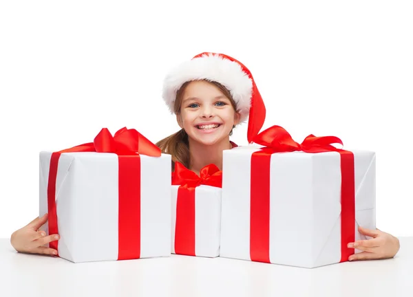 Chica en sombrero de ayudante de santa con muchas cajas de regalo — Foto de Stock