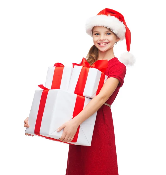 Meisje in helper kerstmuts met vele geschenkdozen — Stockfoto