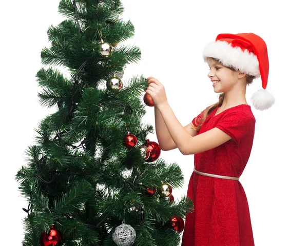 Lachende meisje in helper KERSTMUTS versieren van een boom — Stockfoto