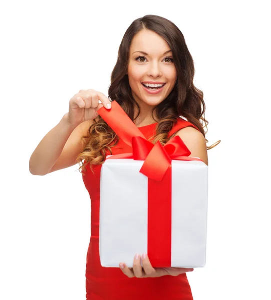 Усміхнена жінка в червоній сукні з подарунковою коробкою — стокове фото