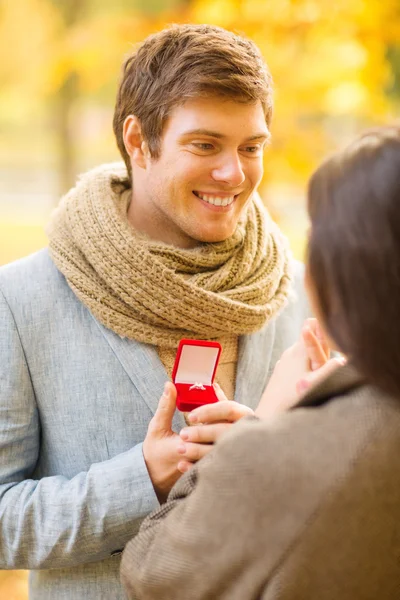 向一个女人在片秋色的公园求婚的男人 — 图库照片