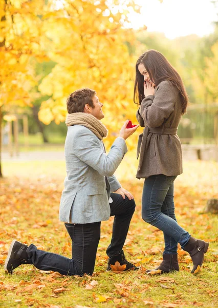 向一个女人在片秋色的公园求婚的男人 — 图库照片