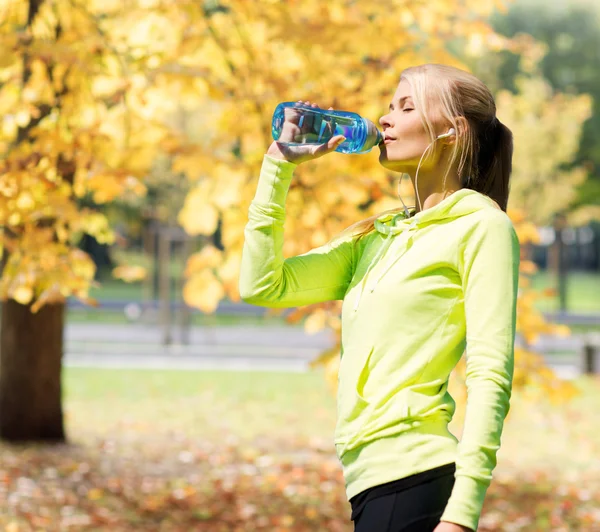 Женщина пьет воду после занятий спортом на открытом воздухе — стоковое фото