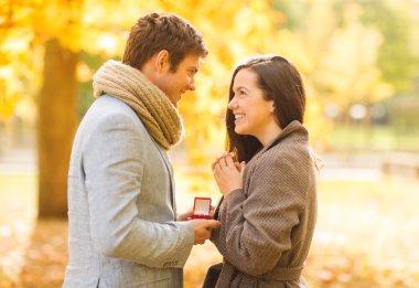 Man proposing to a woman in the autumn park clipart