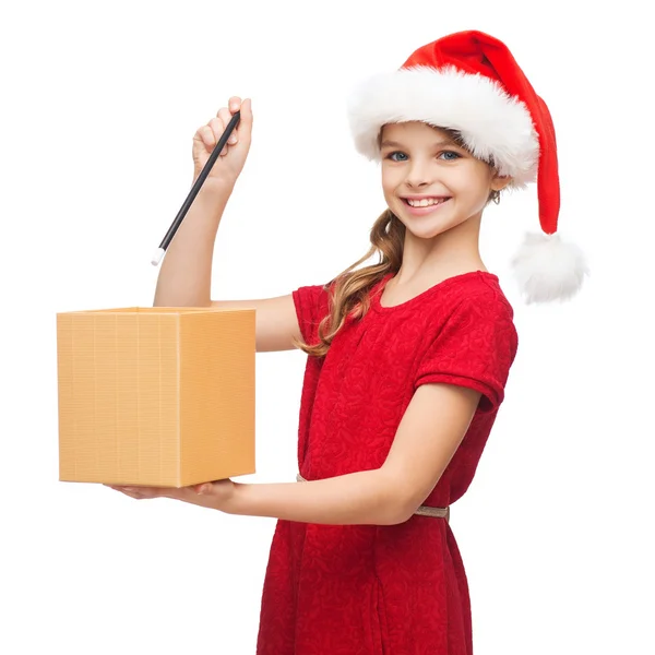 Улыбающаяся девушка в шляпе помощника Санты с подарочной коробкой — стоковое фото