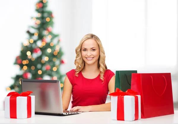 Femme avec boîtes-cadeaux, sacs et ordinateur portable — Photo