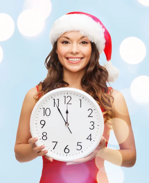 Femme en santa chapeau d'aide avec horloge montrant 12 — Photo