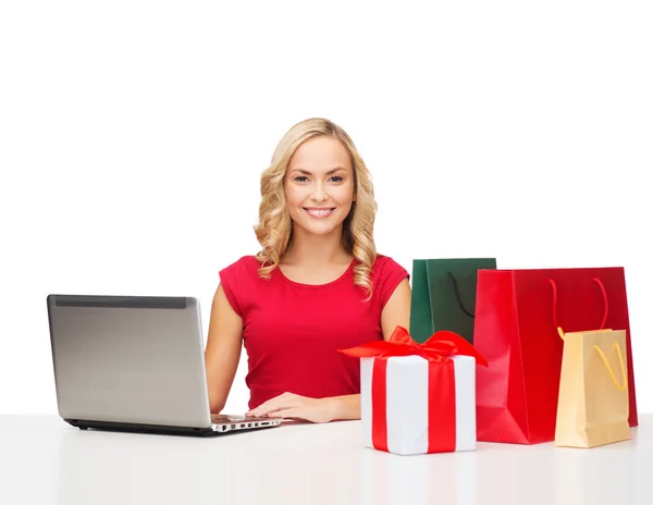 Woman with gift boxes, bags and laptop computer — Stock Photo, Image