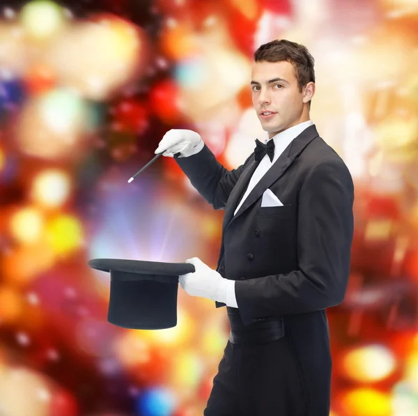 Magician in top hat with magic wand showing trick — Stock Photo, Image