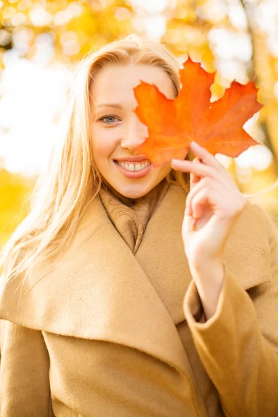 Woman with red marple leaf in the autumn park — Stock Photo, Image