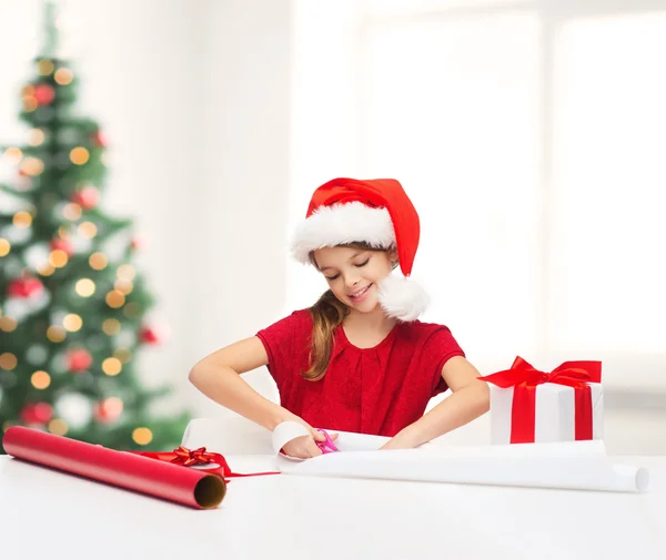 Smiling girl in santa helper hat with gift box — Stock Photo, Image