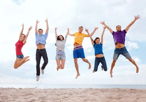 Grupo de amigos pulando na praia — Fotografia de Stock