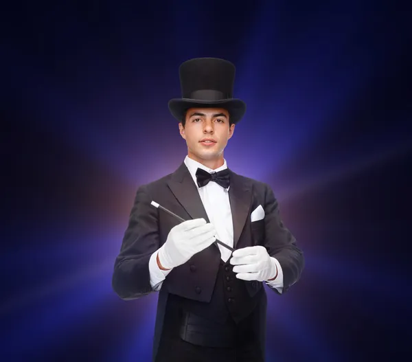 Magician in top hat with magic wand showing trick — Stock Photo, Image