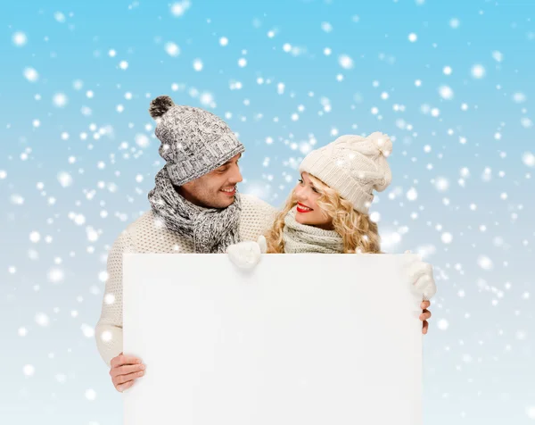 Casal em roupas de inverno com placa branca em branco — Fotografia de Stock