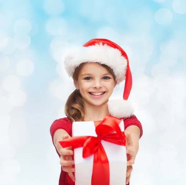 在圣诞老人的助手帽子与礼品盒中的小女孩微笑着 — 图库照片