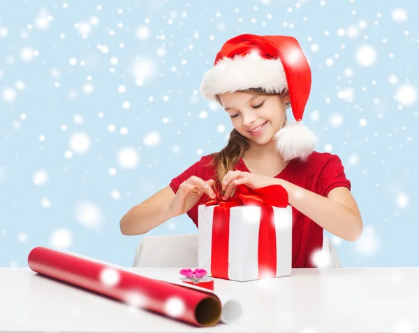 Ragazza sorridente in cappello Babbo Natale con confezione regalo — Foto Stock