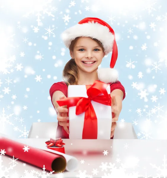 Chica sonriente en sombrero de ayudante de santa con caja de regalo —  Fotos de Stock