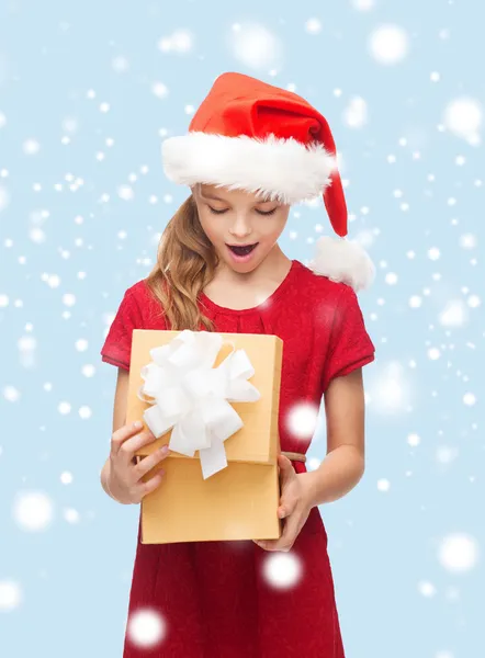 Chica sonriente en sombrero de ayudante de santa con caja de regalo —  Fotos de Stock