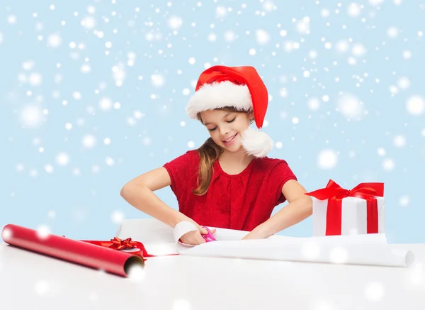 Chica sonriente en sombrero de ayudante de santa con caja de regalo — Foto de Stock