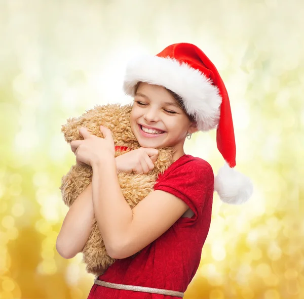 Χαμογελαστό κορίτσι στο santa καπέλο βοηθός με αρκουδάκι — Φωτογραφία Αρχείου